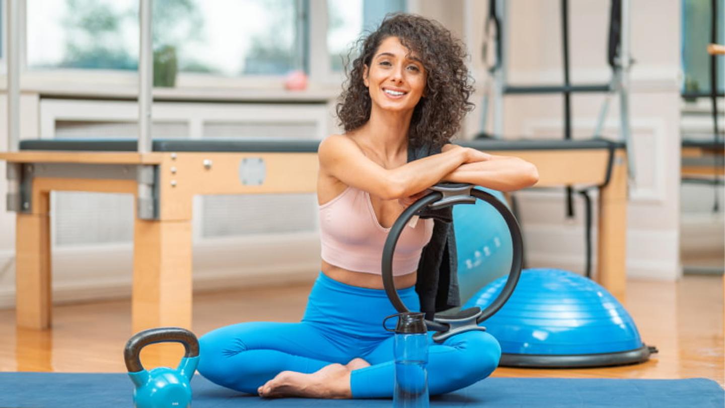 Female Pilates Instructor smiling with pilates equipment.