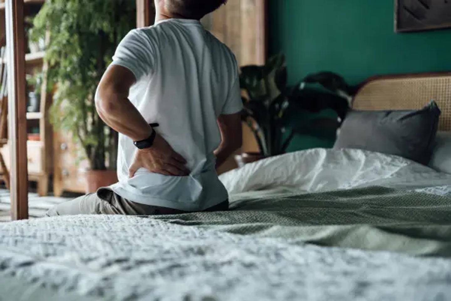Rear view of senior Asian man suffering from backache, massaging aching muscles