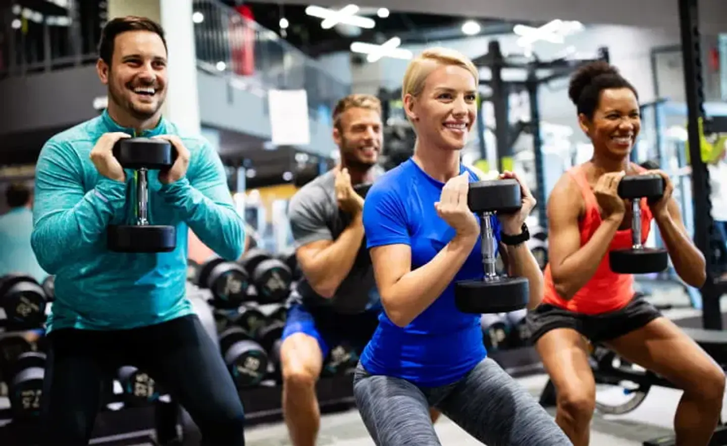 Group Fitness Instructors squatting with dumbbells