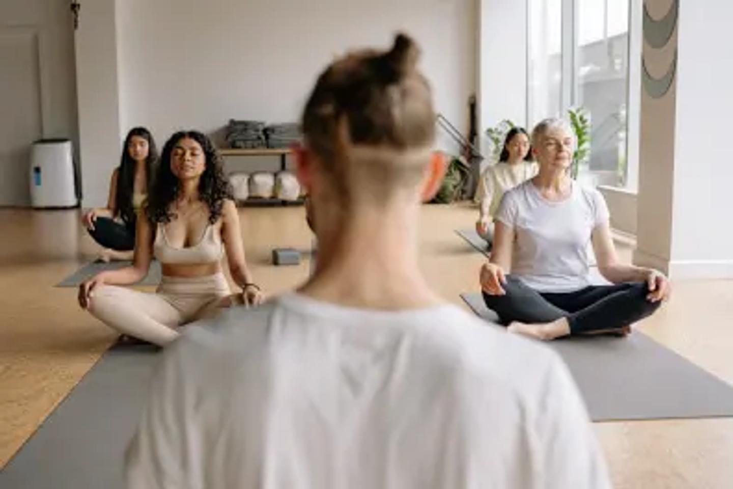 ISSA instructor looking at students over the shoulder doing yoga