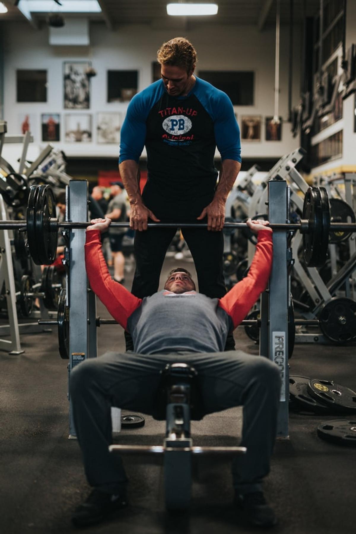Trainer helping client with bench press form