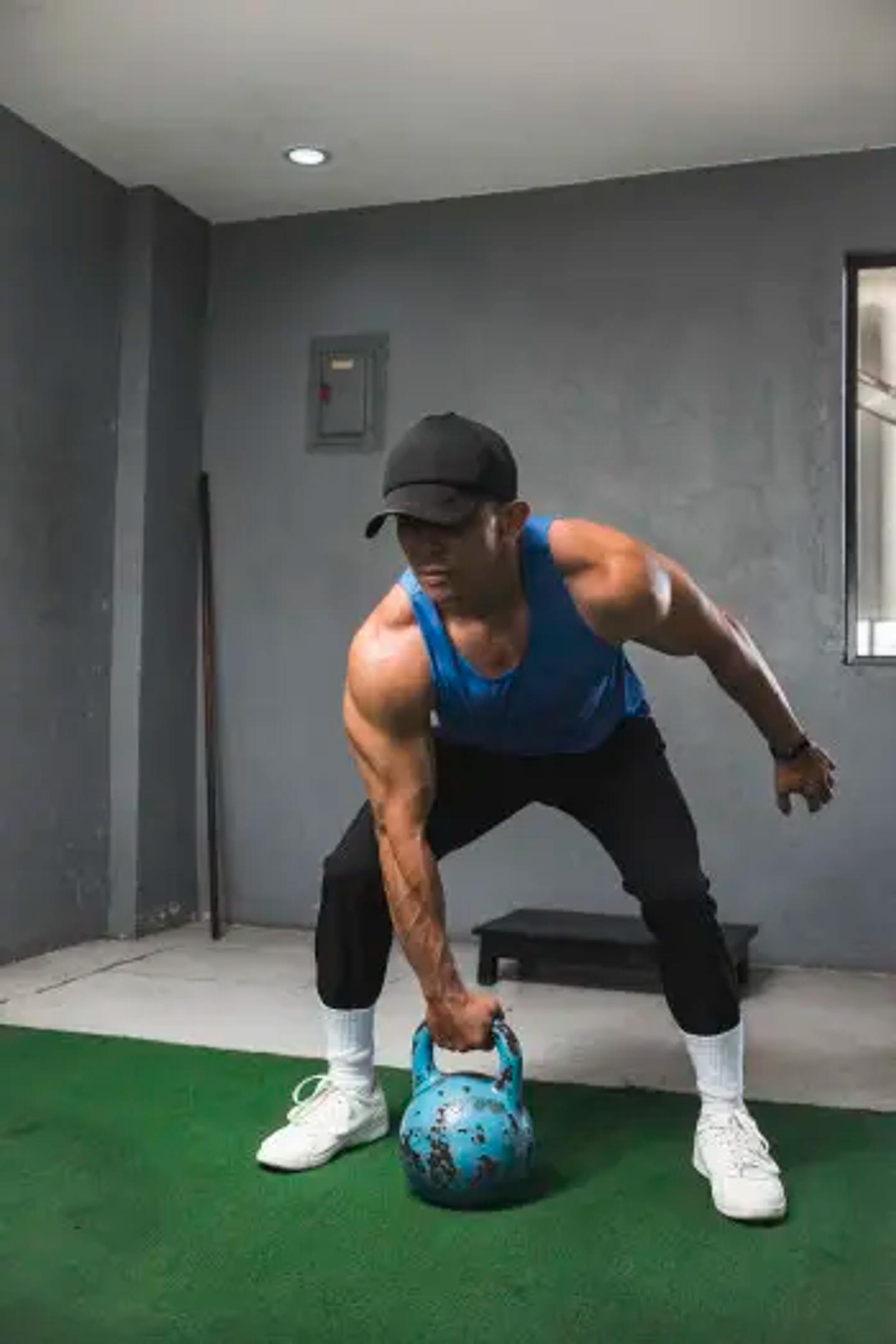 A fit muscular guy prepares to do a set of single arm shoulder thrusters
